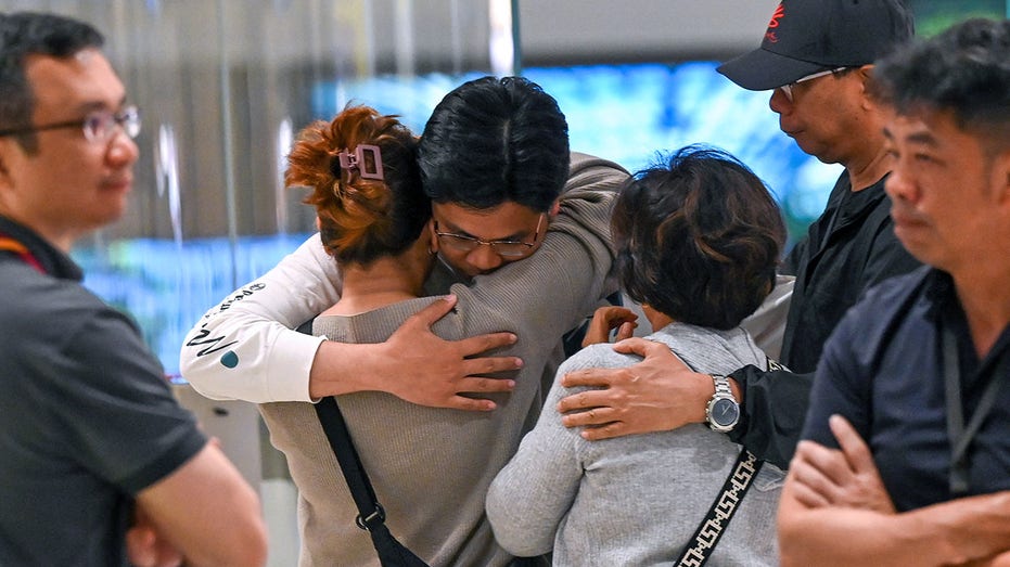 Passengers embrace after Singapore Airlines flight arrives in Singapore