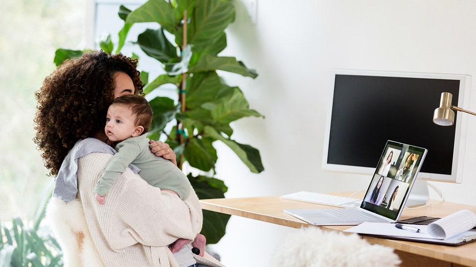 a woman holds her baby while working