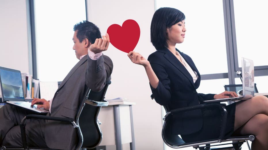 man and woman exchanging a heart at work