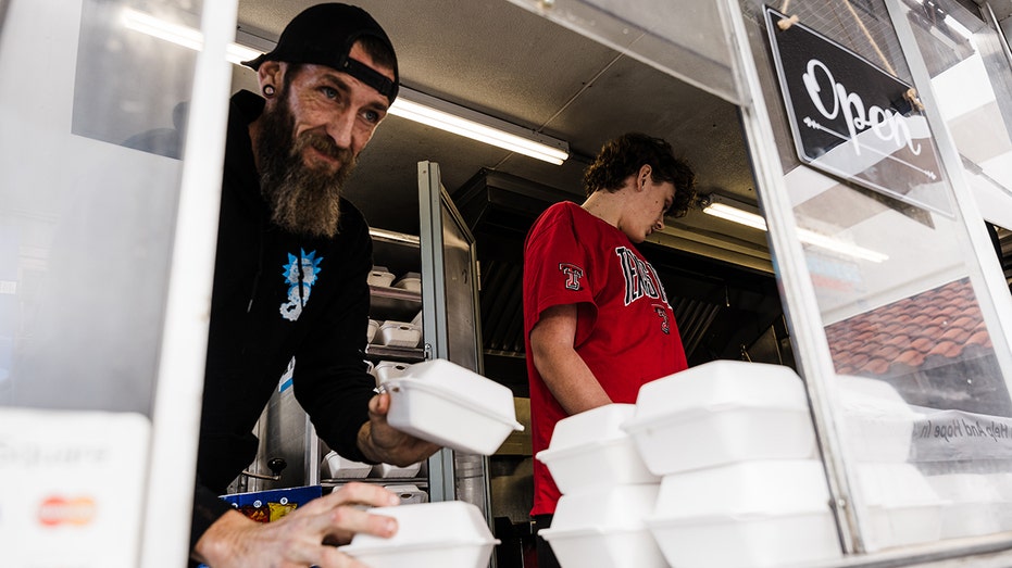a food truck worker serves a meal in a to go box