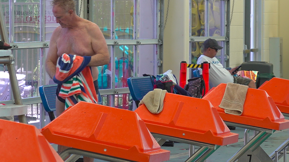 A man drying himself off at a pool.