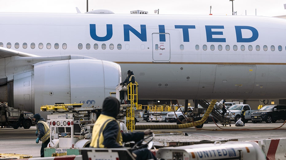 United Airlines Boeing 777-200 airplane at a gate with workers around