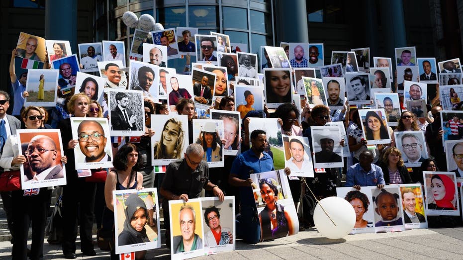 Boeing victims' relatives hold up pictures of victims at DOT headquarters