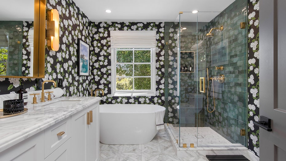 A bathroom with a bathtub, shower and black and white wallpaper