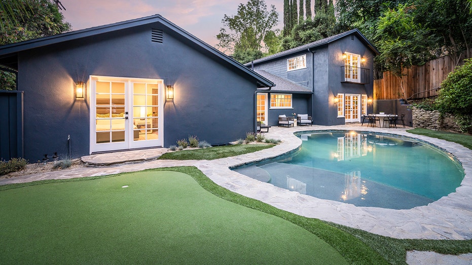 The backyard features a large pool and a putting green.