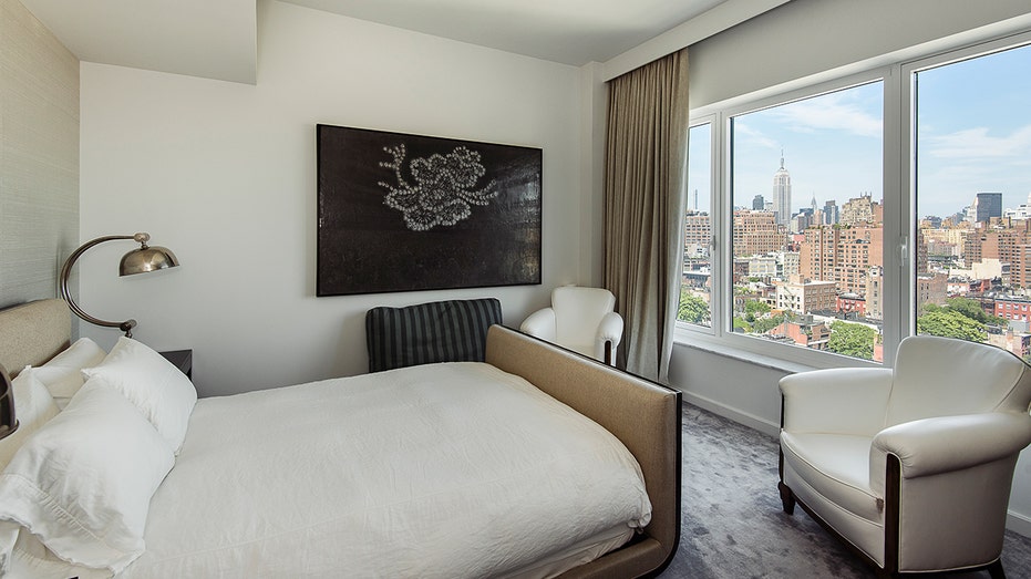 A bedroom with wall art and views of the city