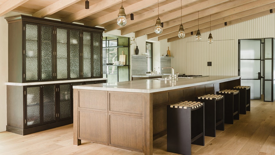 Light oak island in kitchen with beams on the ceiling