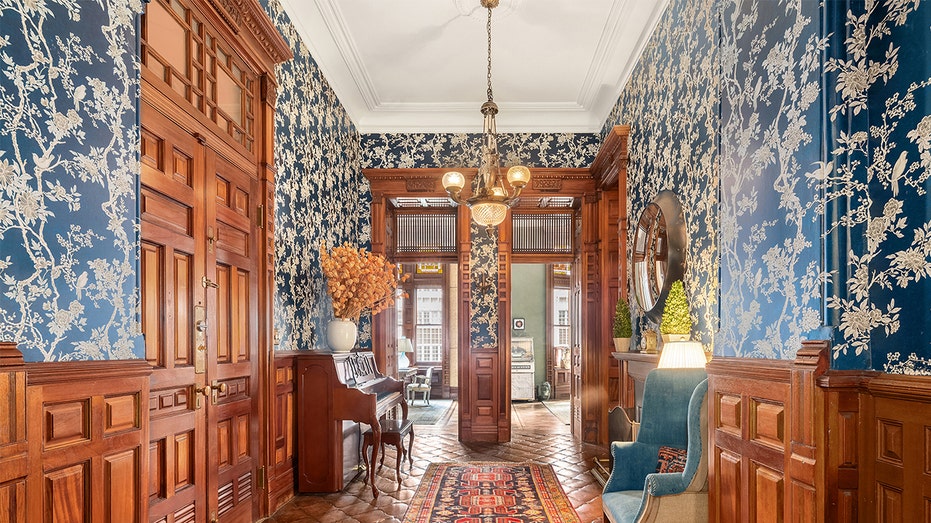 Walkway into Jessica Chastain's home with blue fabric wallpaper and mahogany panels