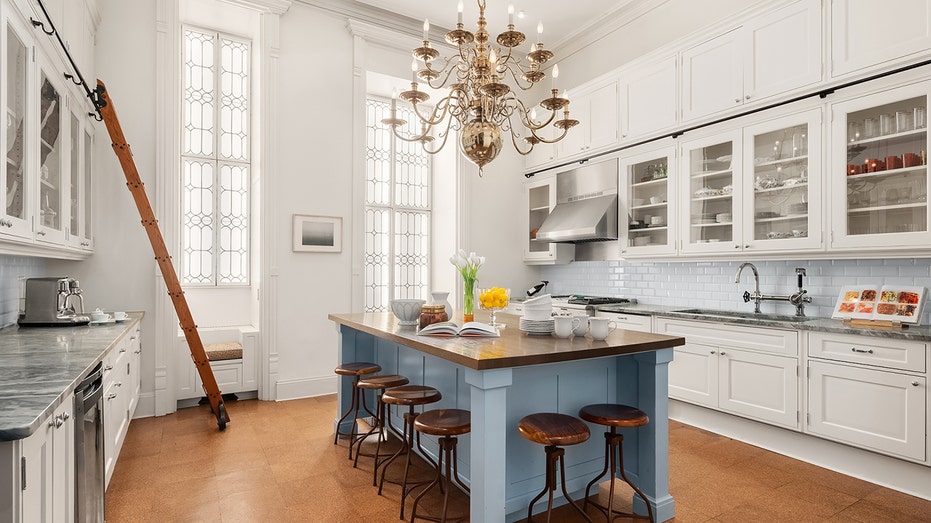 The kitchen with a blue island features top-of-the-line appliances and a ladder