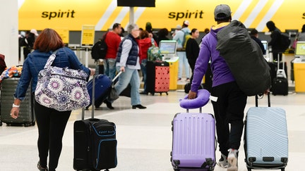 Travelers wheel luggage toward Spirit Airlines check-in desk at George Bush Intercontinental Airport, Tuesday, Nov. 21, 2023, in Houston. - Fox Business News