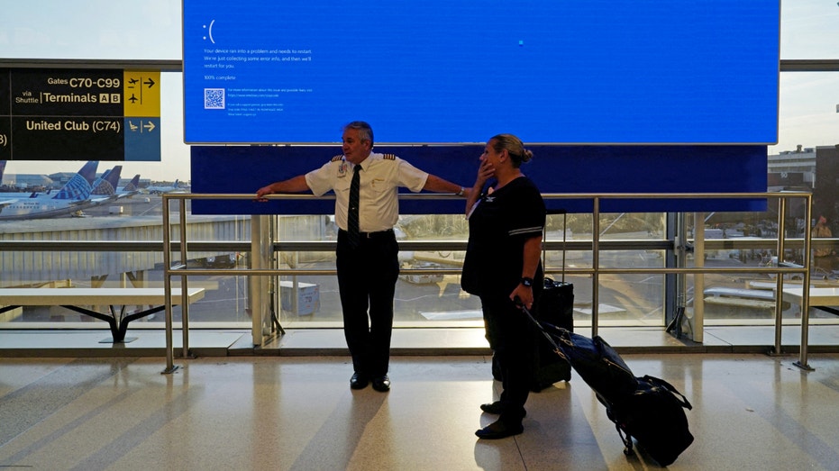 United Airlines employees wait by a departures monitor displaying a blue error screen after United Airlines and other airlines grounded flights due to a worldwide tech outage caused by an update to CrowdStrike's "Falcon Sensor" software which crashed Microsoft Windows systems, in Newark, New Jersey, U.S., July 19, 2024. REUTERS/Bing Guan