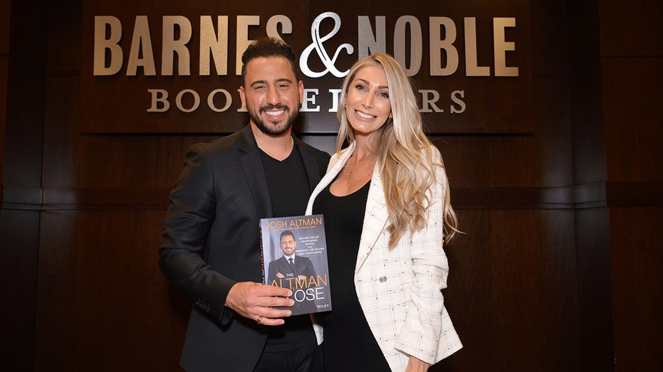 Josh Altman and Heather Altman posing together with his book