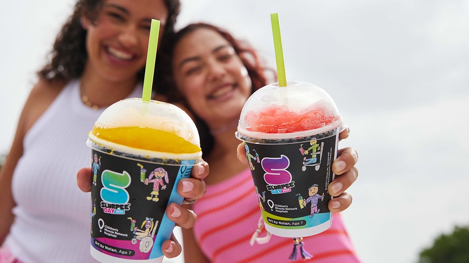 Two women holding Slurpees.