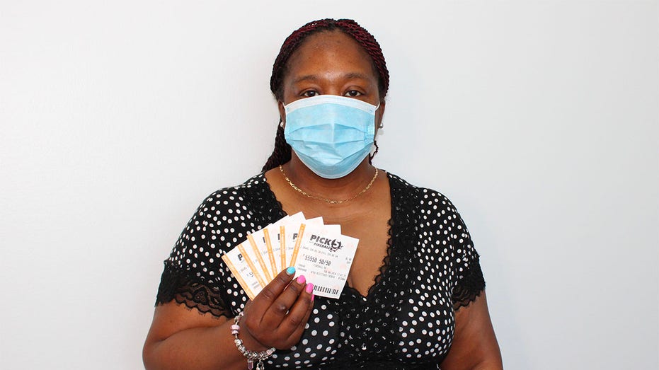 Woman in mask holding lottery tickets.