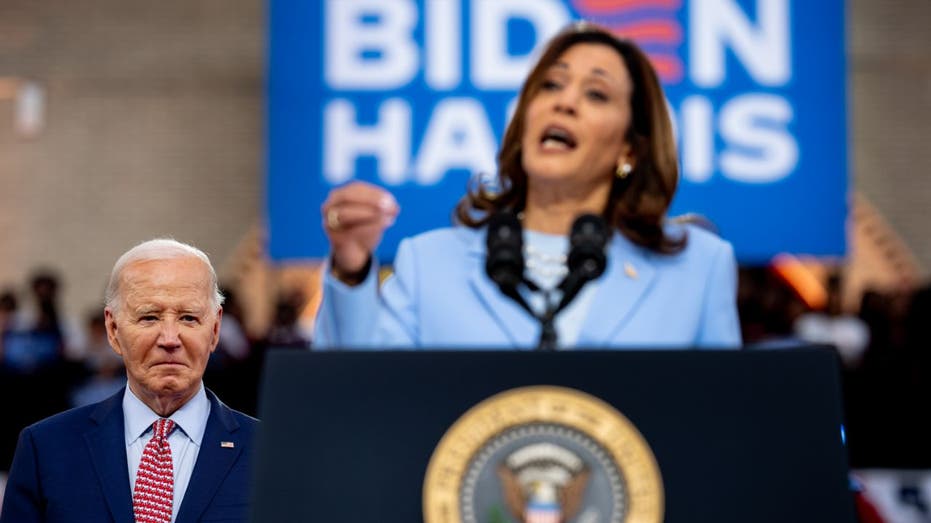 Biden looks on while Harris speaks from podium