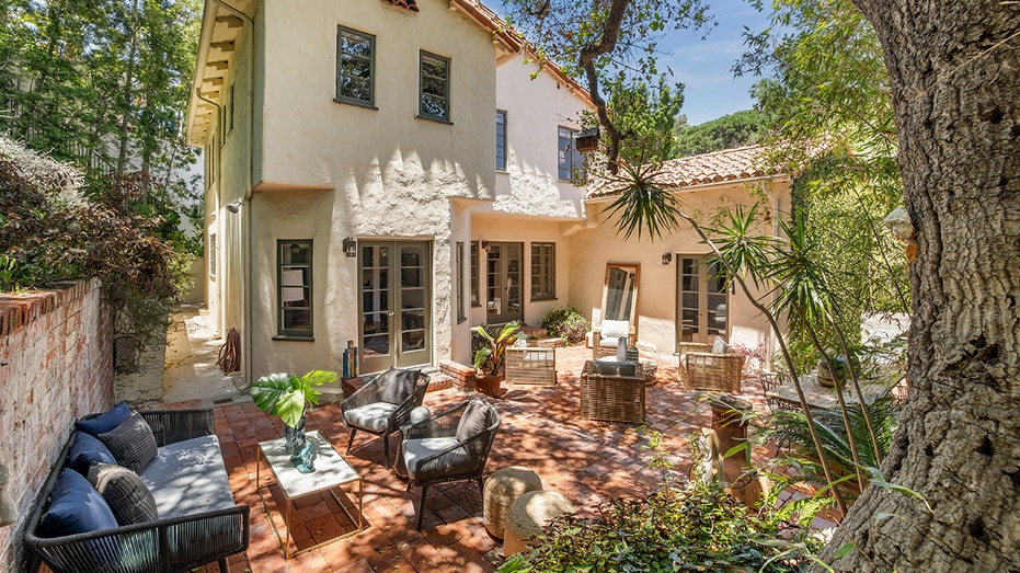 The backyard features multiple seating areas and beautiful landscaping.