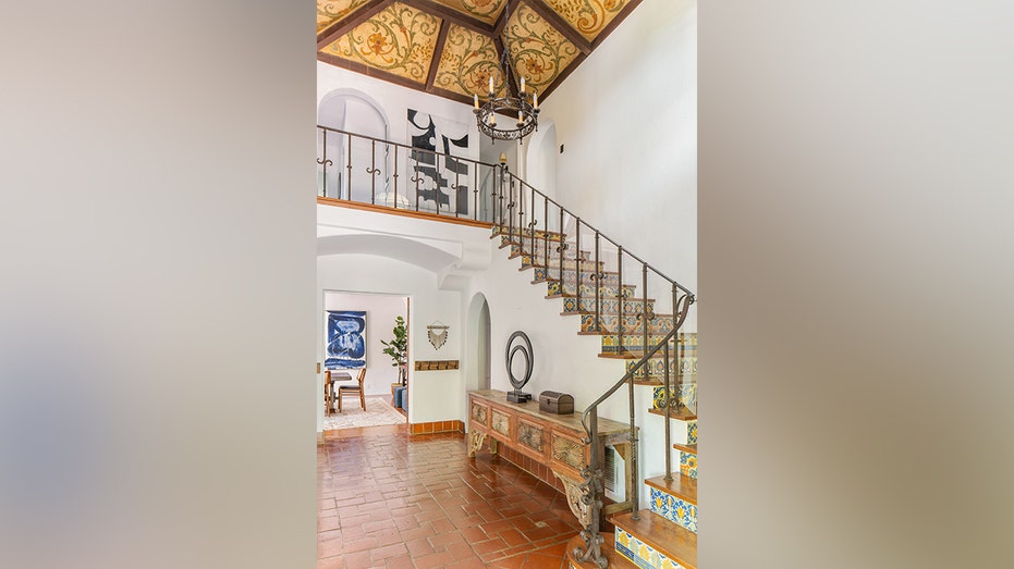 Upon entering the home, guests are greeted with beautiful artwork on the ceiling and a staircase with vintage tiles.