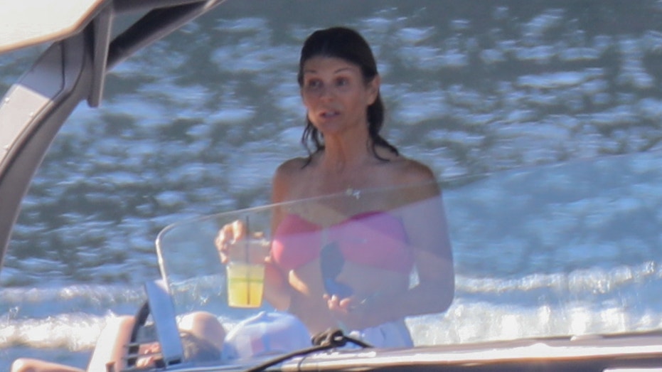 Lori Loughlin in a pink bikini enjoys a drink on a boat