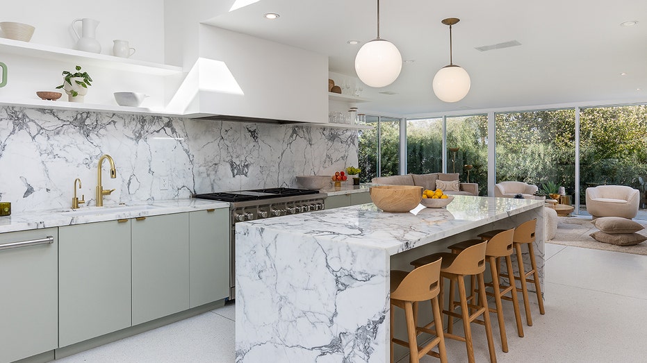 The kitchen features marble countertops and backsplash with green and gray hues. 