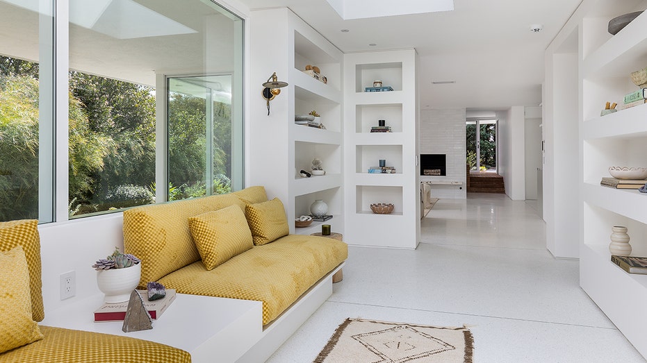 The library alcove boasts unique built-in yellow sofas beneath large window.