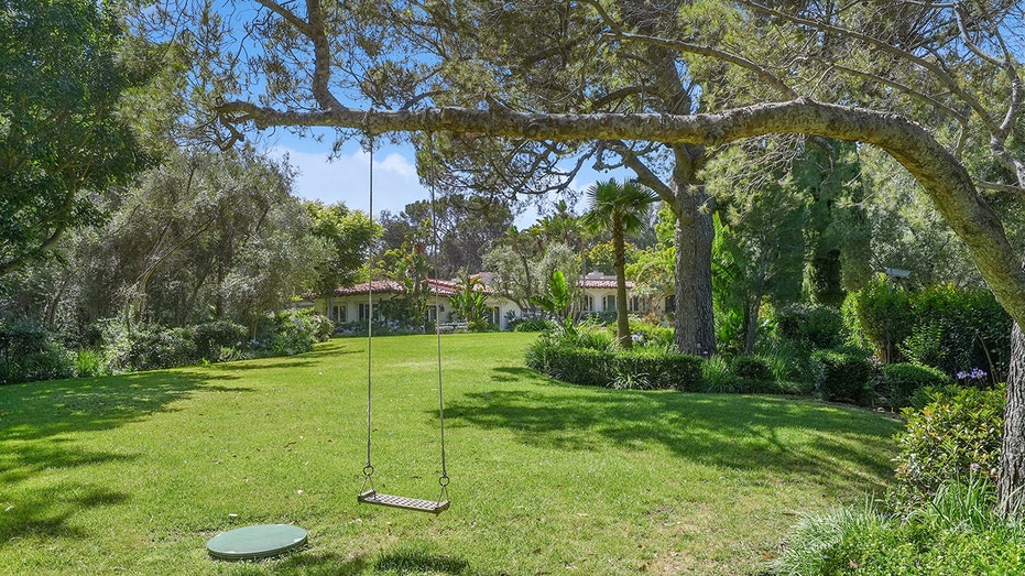 The home sits on 2.6 acres of land, and features lush green grass and many trees.