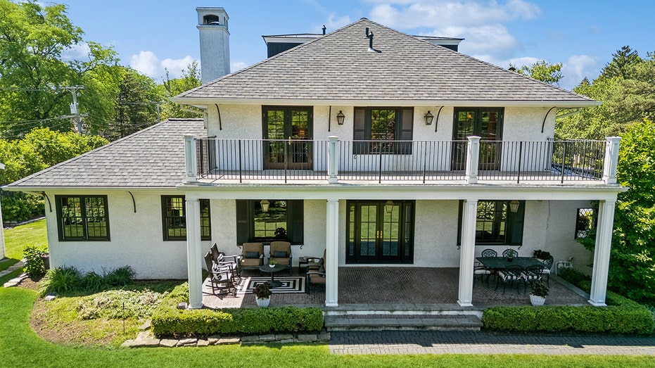 The outside of the home features many seating areas, both under a patio and on the grass.