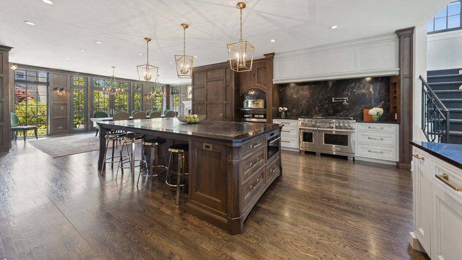 The kitchen features an oversized center island with additional seating, and white marble countertops.