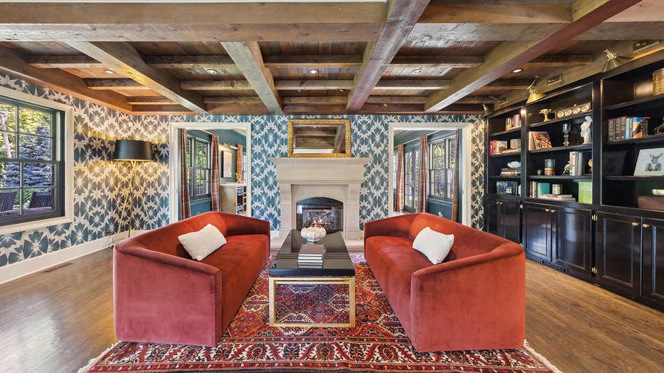 The living room features colorful wallpaper and a double sided fireplace.