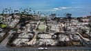 LAHAINA, HAWAII - OCTOBER 09: In an aerial view, a recovery vehicle drives past burned structures and cars two months after a devastating wildfire on October 09, 2023 in Lahaina, Hawaii. The wind-whipped wildfire on August 8th killed at least 98 people while displacing thousands more and destroying over 2,000 buildings in the historic town, most of which were homes. A phased reopening of tourist resort areas in west Maui began October 8th on the two-month anniversary of the deadliest wildfire in modern U.S. history. 