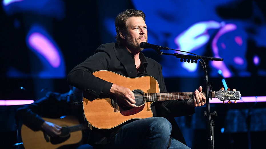 Blake Shelton sitting on stage with a guitar