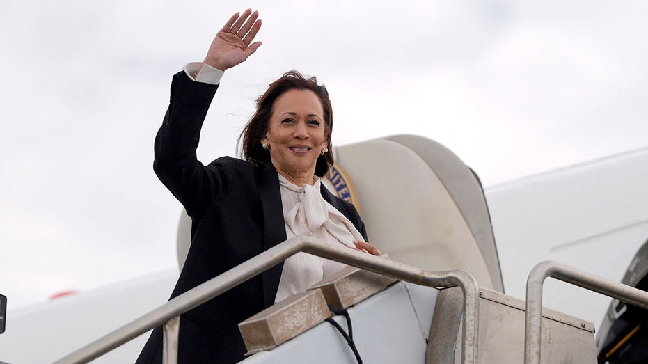 Kamala Harris wedelt mit der Hand auf den Stufen der Air Force Two