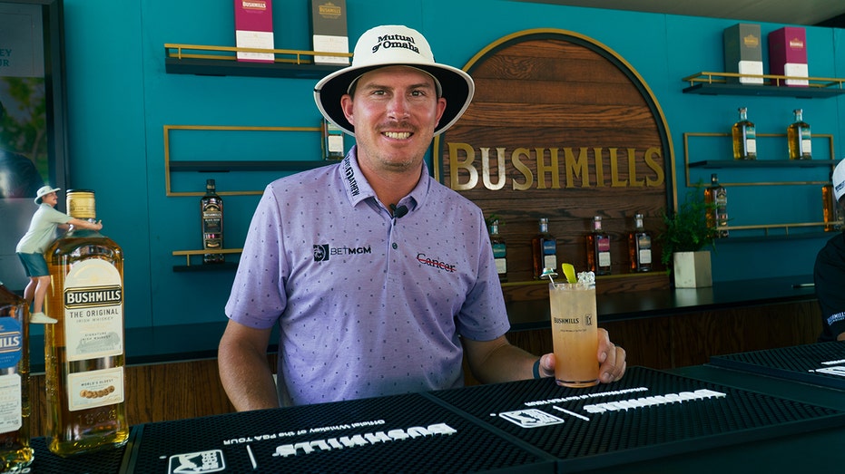 Joel Dahmen poses behind bar