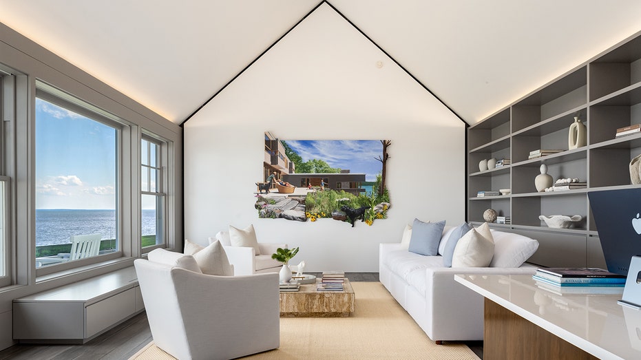 A room with built-in shelves a window and white furniture.