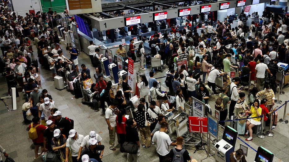 Air Asia passengers wait in line after CrowdStrike outage delays flights.