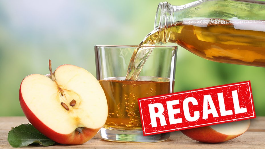 Apple cut in half next to a glass of apple juice that is being filled by a larger cup of apple juice.