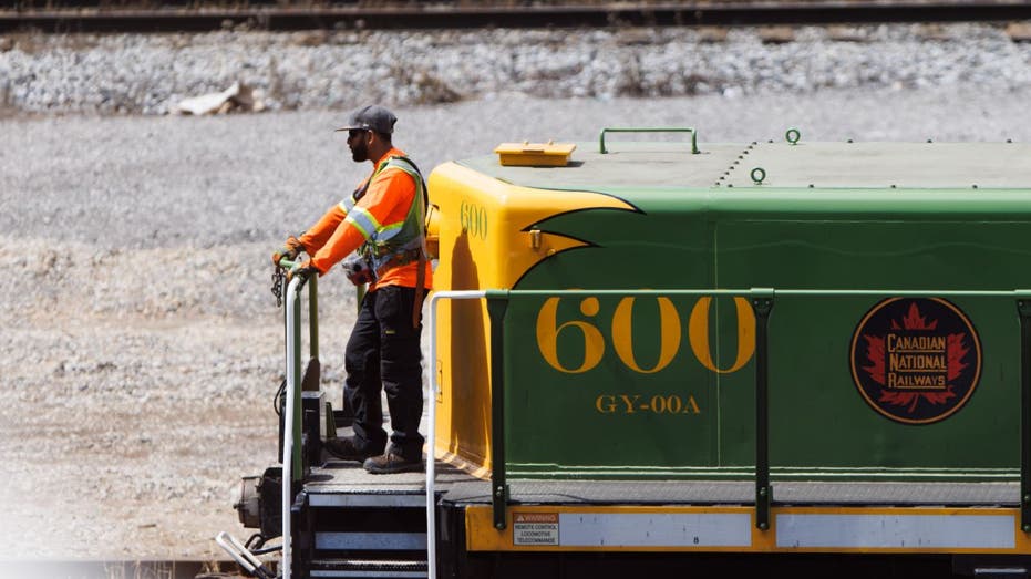 worker on back of Canadian rail car