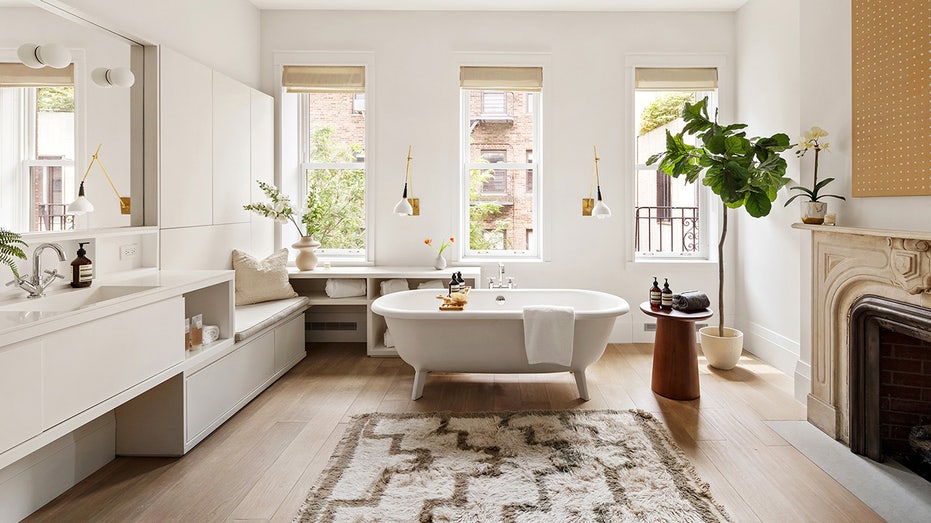 The master bathroom with a classic bathtub and printed carpet