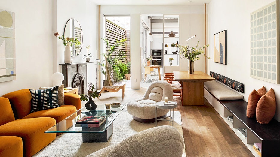 Living space with boucle chairs a kitchen and terrace in the background