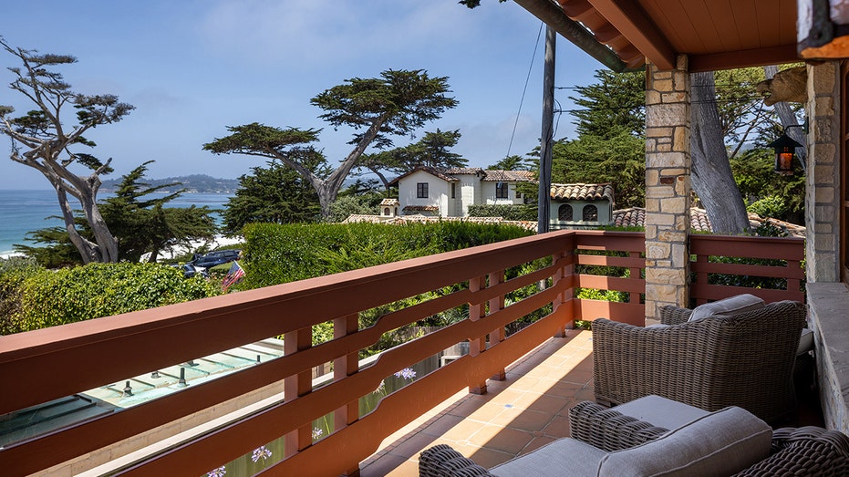 The primary bedroom features a private balcony with seating and an ocean view.