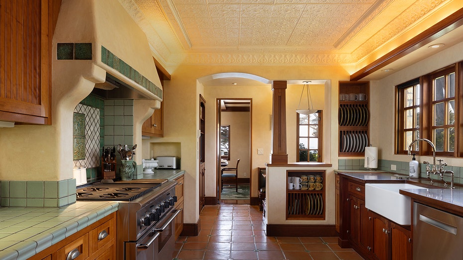 The kitchen has tile floors, green tile countertops and cream walls.