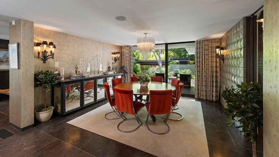 The dining room features wallpaper on one wall and pointy silver panels on the other.