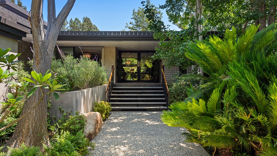 The pebble-filled walkway leads to the French glass doors that open into the interior of the home.