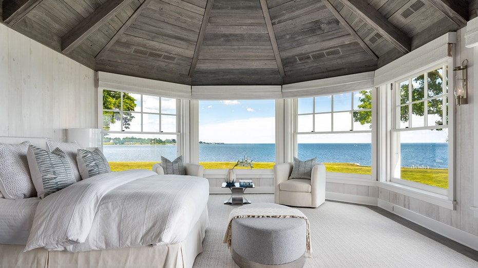 The primary bedroom features a rustic wood ceiling and views of the ocean.