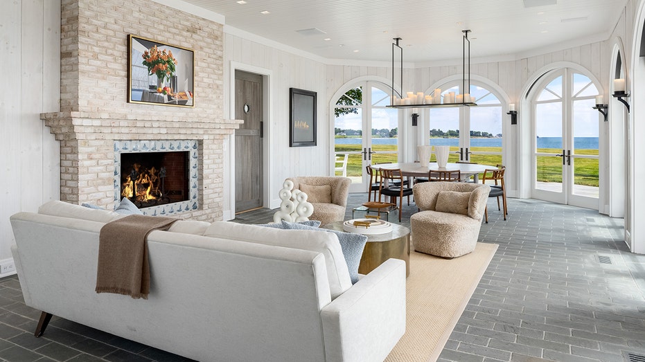 The sun room features a wood-burning fireplace and is surrounded by floor to ceiling windows.