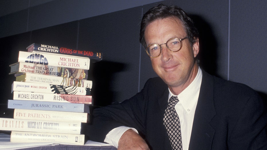 Michael Crichton next to a stack of his books