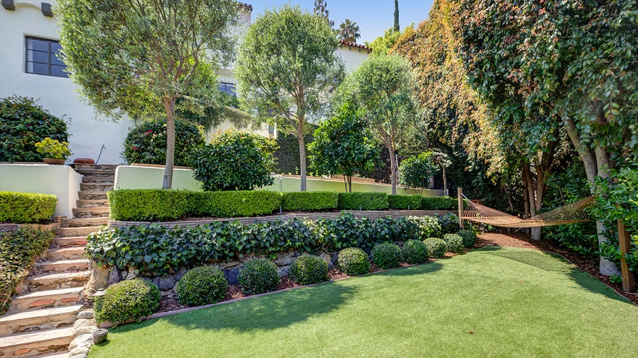 The backyard includes a large lawn with a hammock.