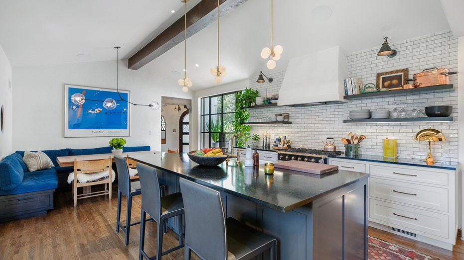 The kitchen includes a large central island and a dining area in the corner.