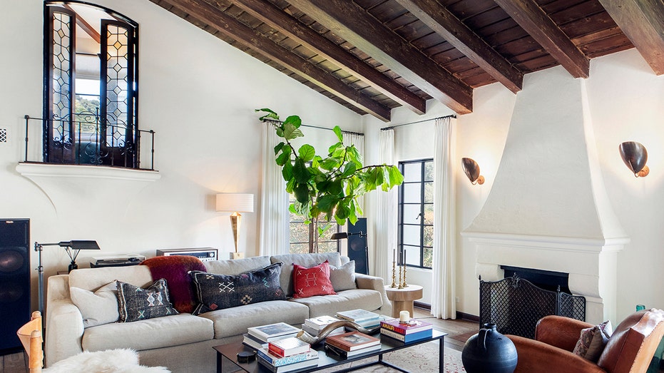 The living room features exposed wood vaulted ceilings, a fireplace and a Juliet balcony.