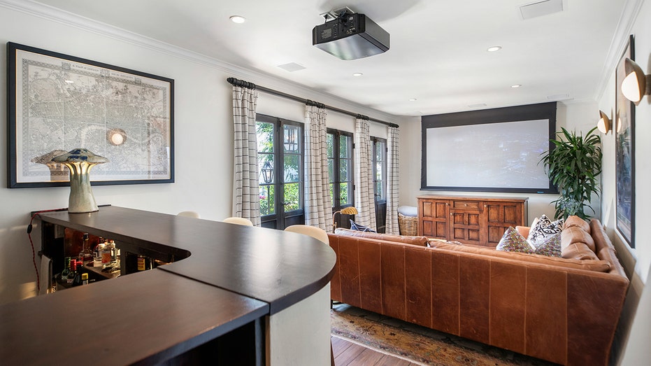 The home features a movie theater with a large projector and a bar.