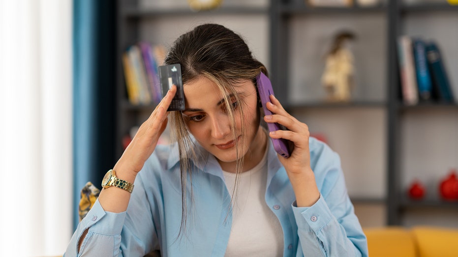 Woman stressed on the phone with a credit card